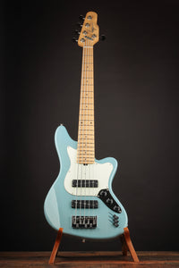 Blue electric bass guitar on a stand against a dark background