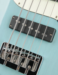 Close-up of a bass guitar's bridge and strings on a light blue background