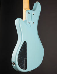 Light blue electric bass guitar on a black background, back view