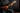 Person playing a mandolin against a dark background