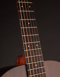 Close-up of a guitar neck with dark wood finish on a black background