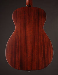 Back view of a wooden acoustic guitar on a dark background