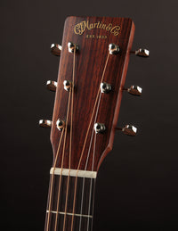 Close-up of a Martin guitar headstock with brand name on a dark background