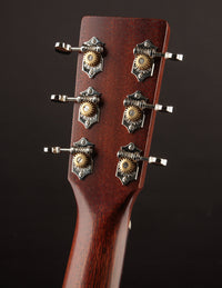 Close-up of a guitar headstock with tuning pegs on a dark background