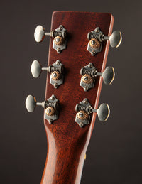 Close-up of a guitar headstock with tuning pegs on a dark background