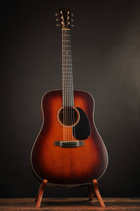 Martin acoustic guitar on a stand against a dark background