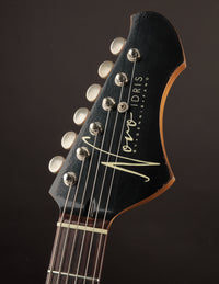 Close-up of a guitar headstock with 'Novo' branding on a dark background