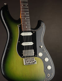 Green and black electric guitar on a dark background