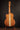 Classical guitar on a stand against a dark background, from the back