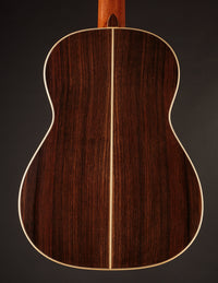 Back view of a classical acoustic guitar on a dark background