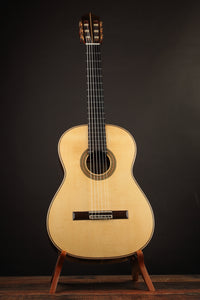 Classical acoustic guitar on a stand against a dark background