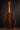 Classical acoustic guitar on a stand against a dark background, from the back