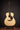 Acoustic guitar on a stand against a dark background
