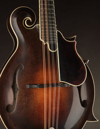 Close-up of a mandolin with a dark brown finish on a black background