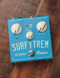 A blue guitar effect pedal with knobs and switches, labeled 'SURFYTREM Deluxe'.