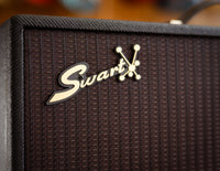 Close up of Swart amplifier with guitars in the background
