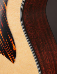 Close up of binding and pickguard on a Taylor acoustic guitar on a dark background