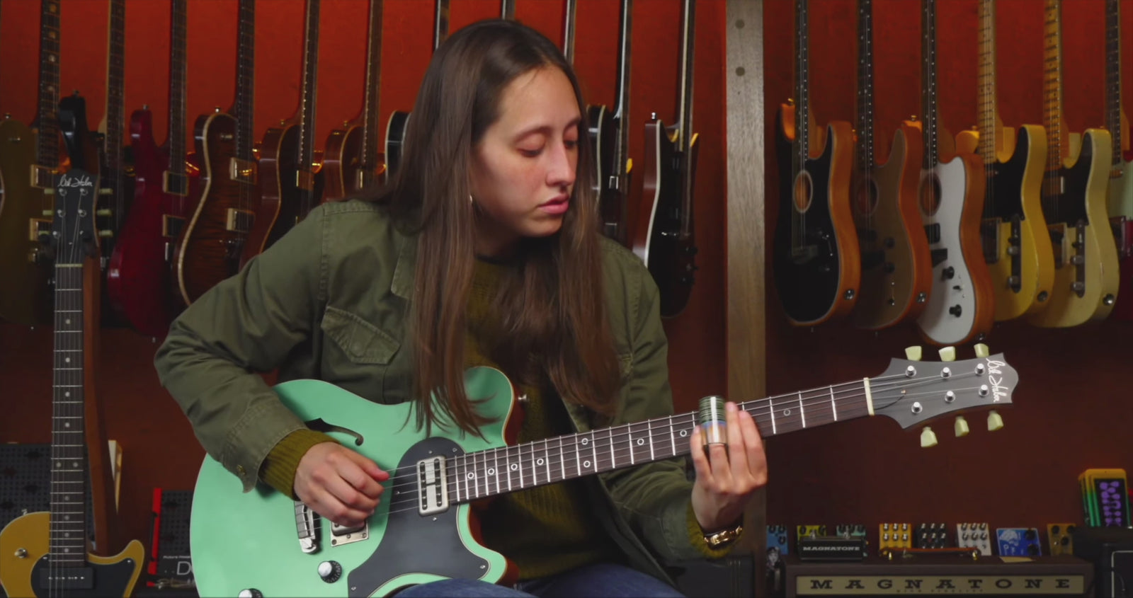 Rachael, a Music Emporium staff member, plays slide on a green Nik Huber electric guitar.
