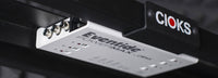 Underside view of a black Cioks GRIP mounting bracket securing a white CIOKS Eventide power supply under a PedalTrain pedal board.