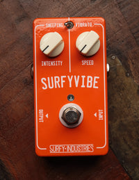 A SurfyVibe guitar effect pedal with knobs for intensity and speed control, and a switch labeled 'sweeping'. It is colored orange with white knobs and black text.