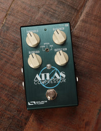 A green guitar compressor pedal with knobs and a pedal switch, labeled 'Atlas Compressor' by Source Audio.